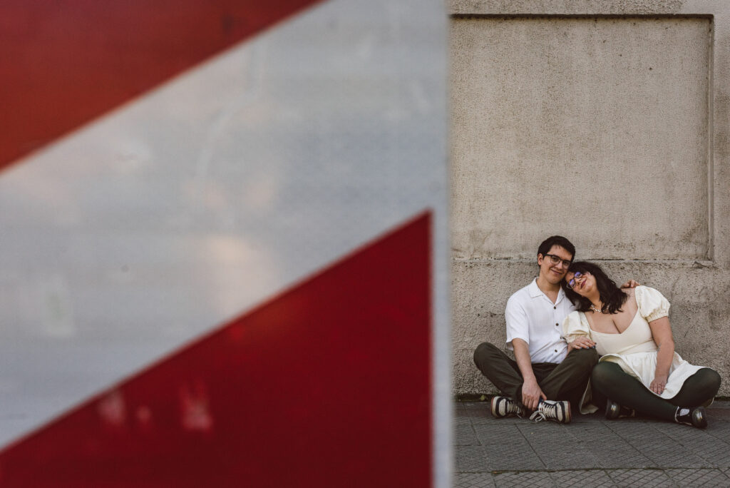 Novios en sesión preboda sentados en el suelo y abrazados.